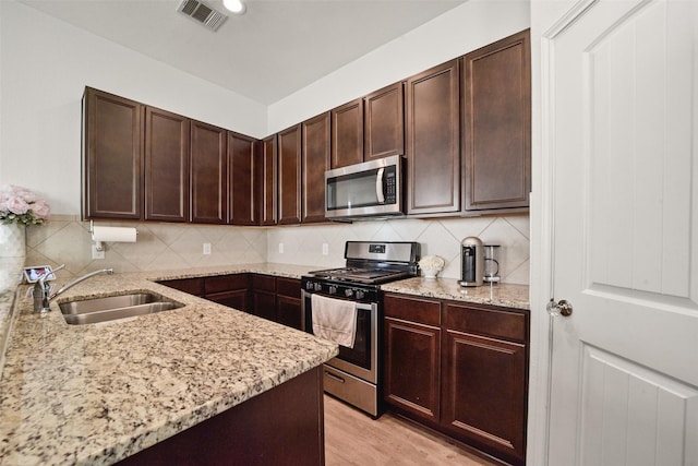 kitchen featuring sink, backsplash, light stone countertops, and appliances with stainless steel finishes