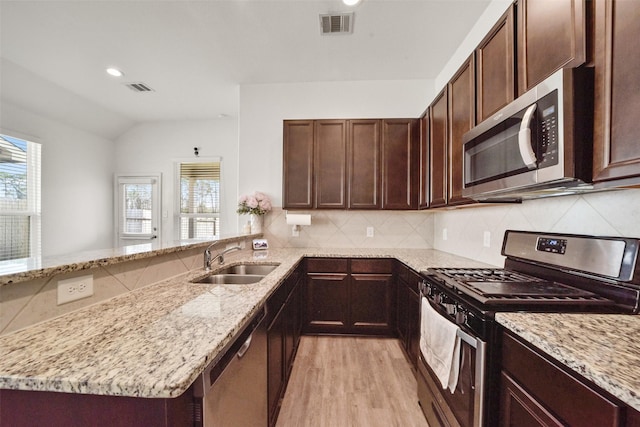 kitchen featuring plenty of natural light, sink, kitchen peninsula, stainless steel appliances, and light stone countertops