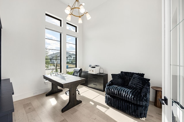 home office with a chandelier, a high ceiling, wood finished floors, and baseboards