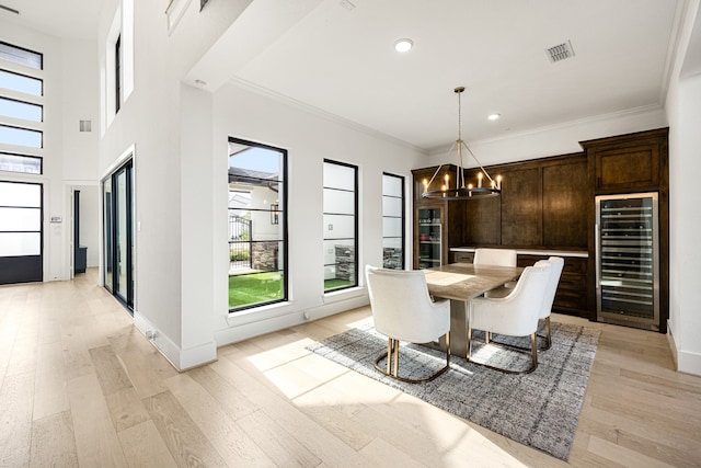 unfurnished dining area with beverage cooler, visible vents, light wood-style flooring, crown molding, and a chandelier