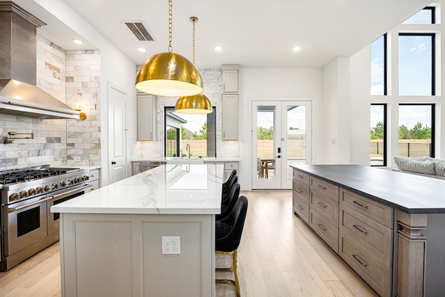 kitchen with a center island, gray cabinets, light wood-style floors, double oven range, and wall chimney exhaust hood