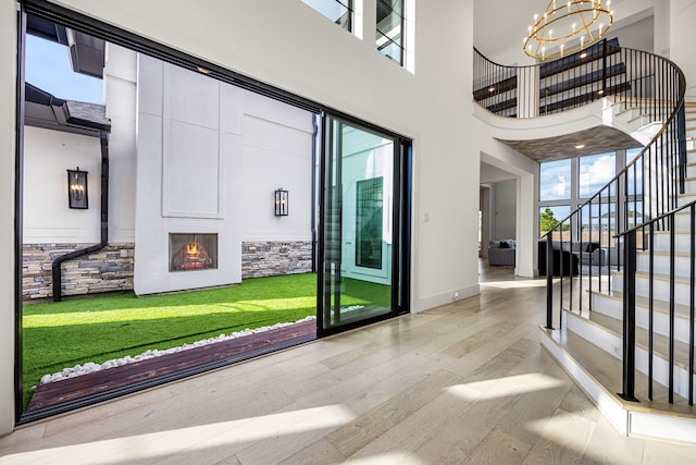 foyer entrance with a chandelier, hardwood / wood-style flooring, a towering ceiling, baseboards, and stairway