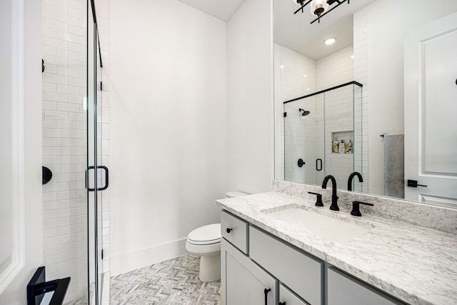 bathroom with toilet, a shower stall, baseboards, and vanity