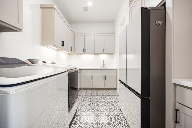 washroom with cabinet space, a sink, visible vents, and washing machine and clothes dryer