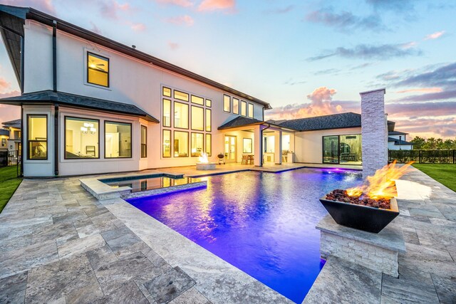 pool at dusk with an in ground hot tub, a patio, and a fire pit