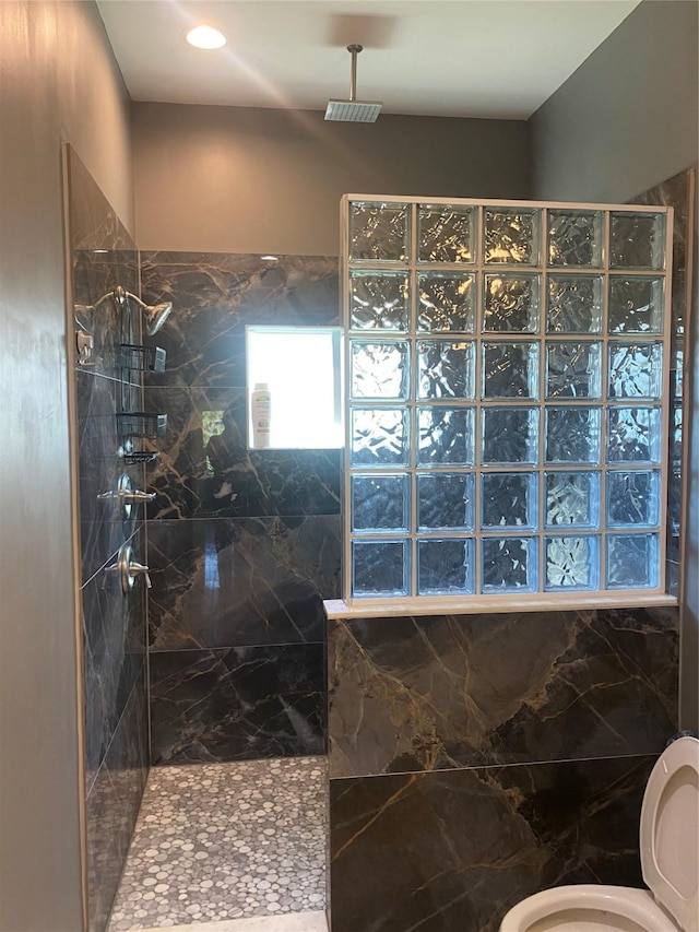 bathroom featuring a tile shower and toilet