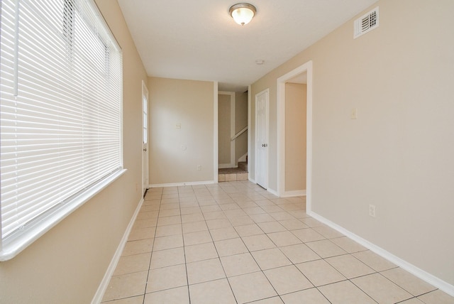 empty room with light tile patterned flooring and plenty of natural light