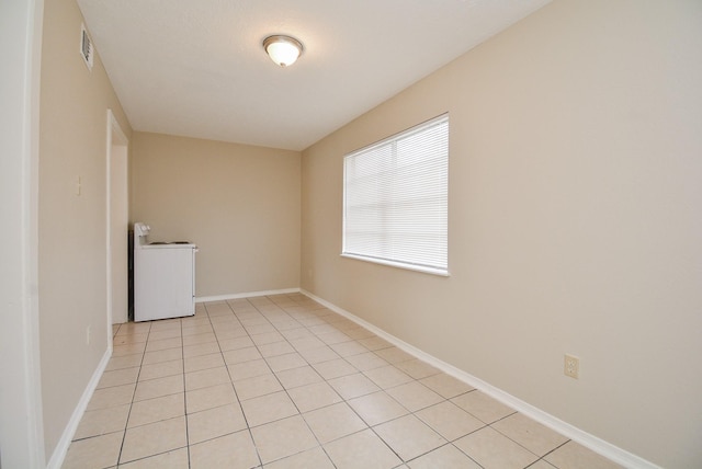 empty room with washer / dryer and light tile patterned floors