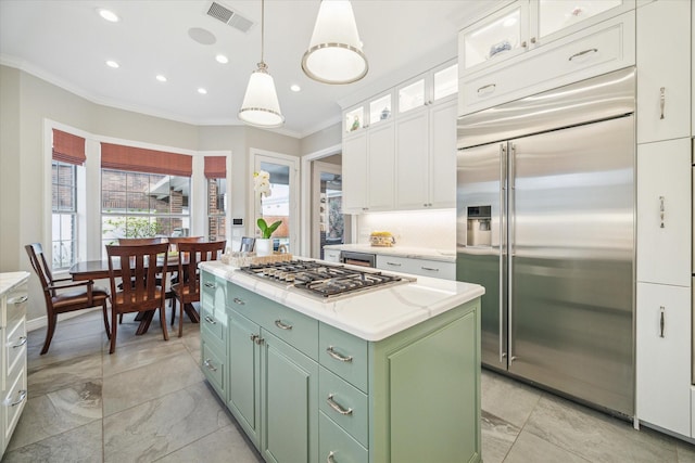 kitchen with white cabinetry, ornamental molding, green cabinets, a kitchen island, and stainless steel appliances