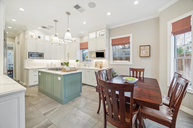 kitchen with hanging light fixtures, stainless steel appliances, a center island, tasteful backsplash, and white cabinets