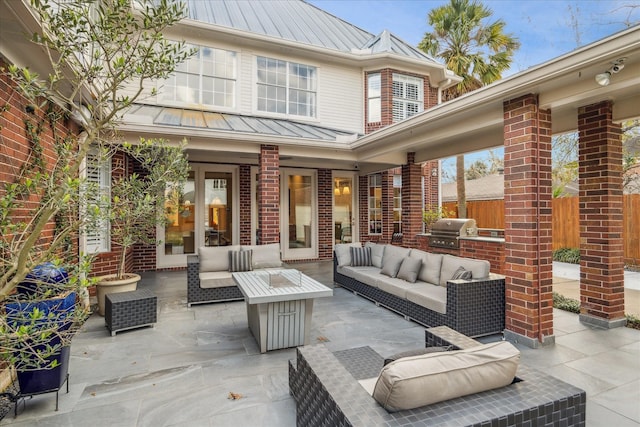 view of patio with area for grilling, exterior kitchen, and an outdoor living space with a fire pit