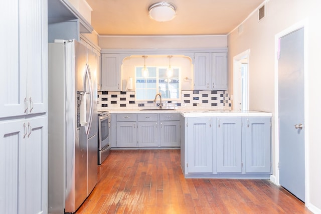 kitchen with appliances with stainless steel finishes, sink, pendant lighting, and backsplash