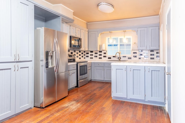 kitchen featuring sink, appliances with stainless steel finishes, gray cabinets, light hardwood / wood-style floors, and decorative backsplash