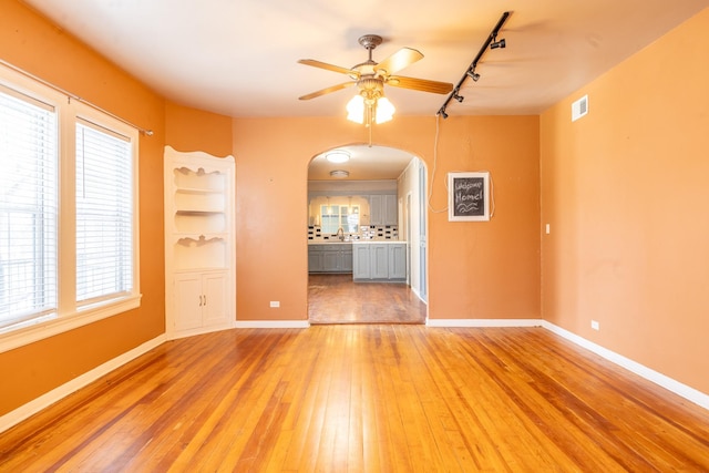 unfurnished room with ceiling fan, wood-type flooring, track lighting, and sink