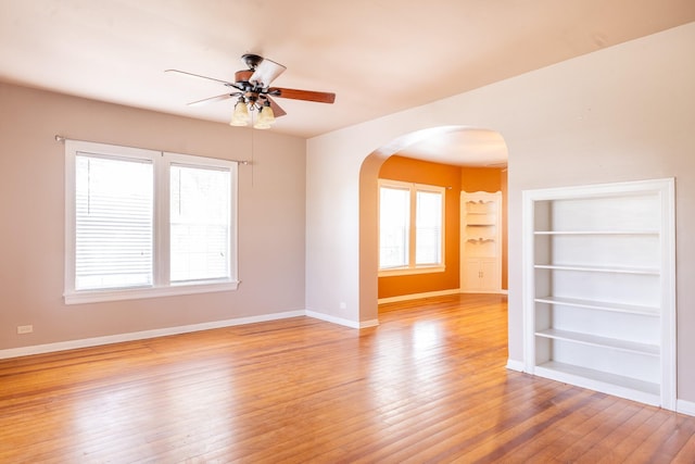 unfurnished room with ceiling fan, built in features, and light wood-type flooring