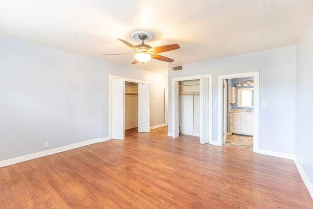 unfurnished bedroom with ceiling fan, two closets, and light wood-type flooring