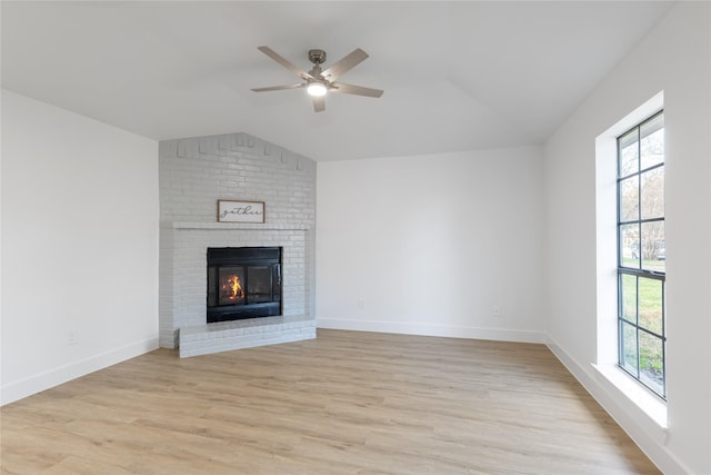 unfurnished living room featuring ceiling fan, vaulted ceiling, a brick fireplace, and light wood-type flooring