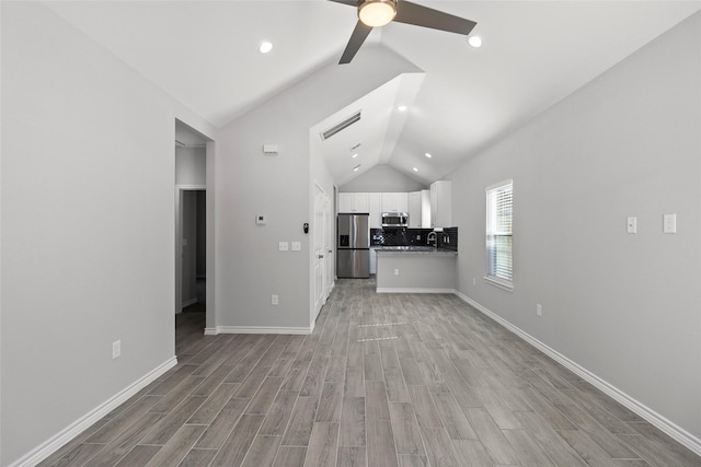 unfurnished living room featuring ceiling fan, lofted ceiling, sink, and light hardwood / wood-style flooring