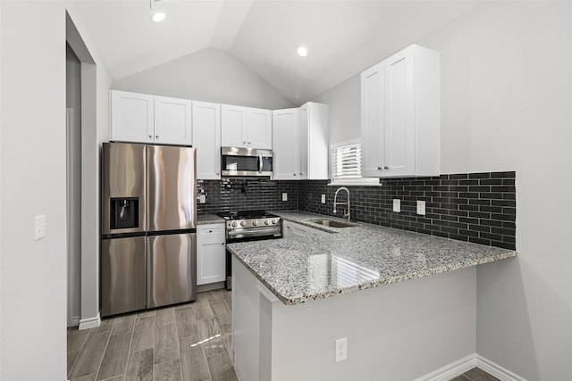 kitchen with white cabinetry, stainless steel appliances, kitchen peninsula, and sink