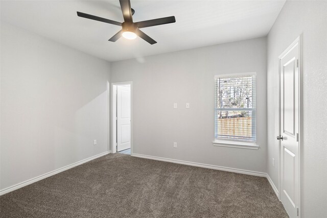 spare room featuring ceiling fan and dark colored carpet