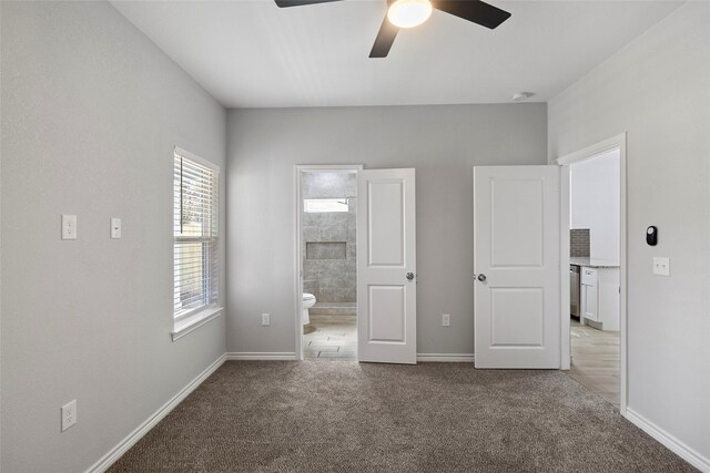 unfurnished bedroom featuring ceiling fan, light colored carpet, and ensuite bathroom