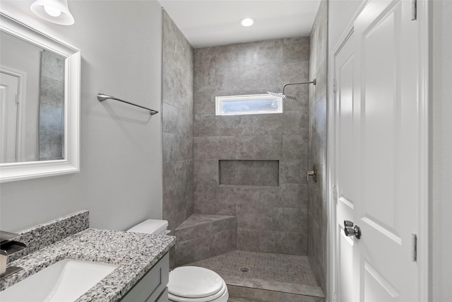 bathroom with vanity, toilet, and a tile shower