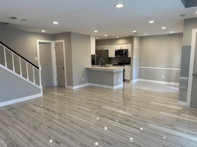 kitchen featuring sink, white cabinets, light hardwood / wood-style floors, kitchen peninsula, and stainless steel appliances