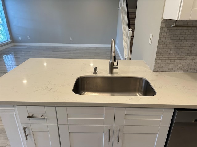 kitchen with white cabinetry, sink, light stone countertops, and dishwasher