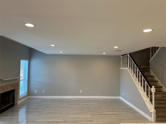 unfurnished living room with a high end fireplace and light wood-type flooring