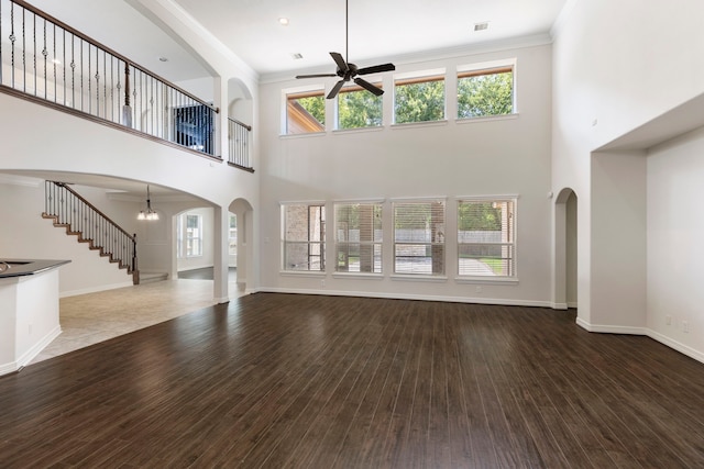 unfurnished living room with hardwood / wood-style flooring, ceiling fan with notable chandelier, ornamental molding, and a healthy amount of sunlight