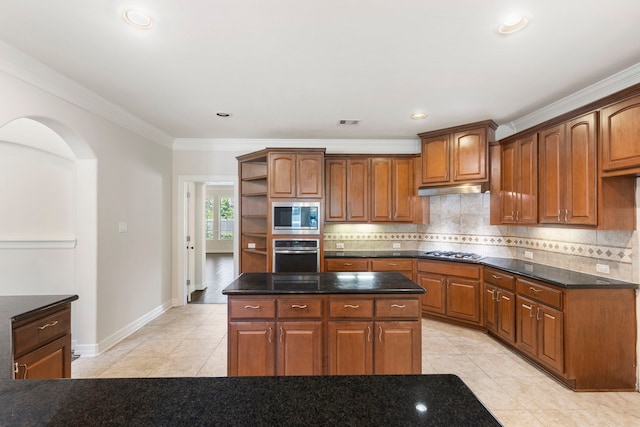 kitchen featuring backsplash, light tile patterned floors, stainless steel appliances, and a center island