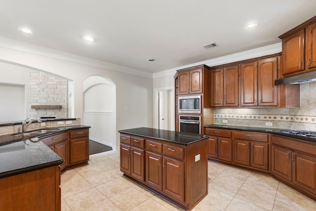 kitchen featuring sink, dark stone countertops, a center island, light tile patterned floors, and stainless steel appliances