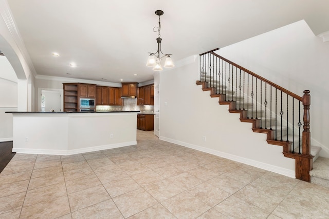 kitchen featuring crown molding, tasteful backsplash, light tile patterned floors, stainless steel microwave, and pendant lighting