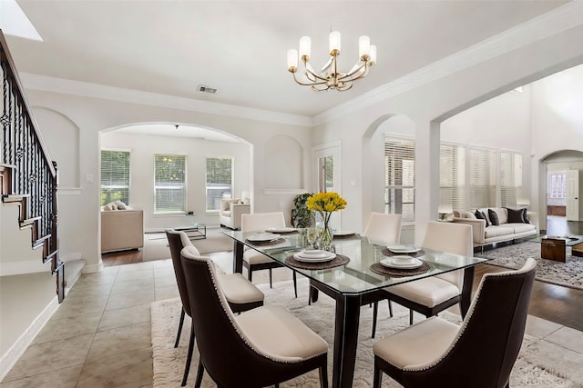 dining space with light tile patterned floors, crown molding, and a chandelier