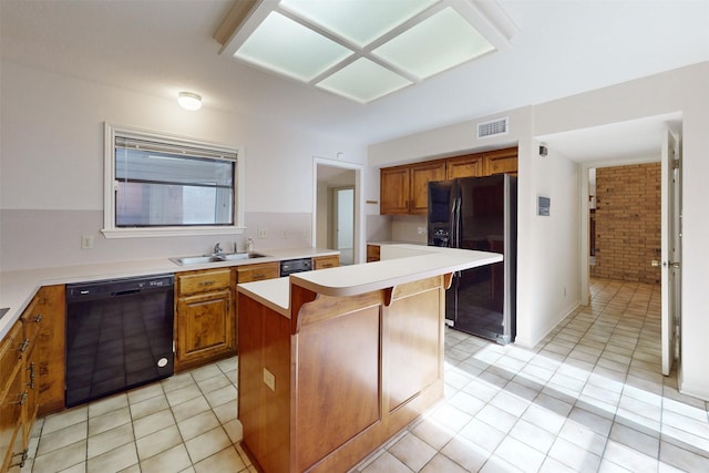 kitchen with sink, light tile patterned floors, a kitchen breakfast bar, a center island, and black appliances