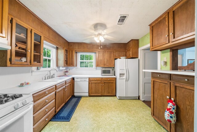 2506 Brazeal St, Waller, TX 77484 - kitchen with brown cabinets, a ceiling fan, a sink, visible vents, and white appliances