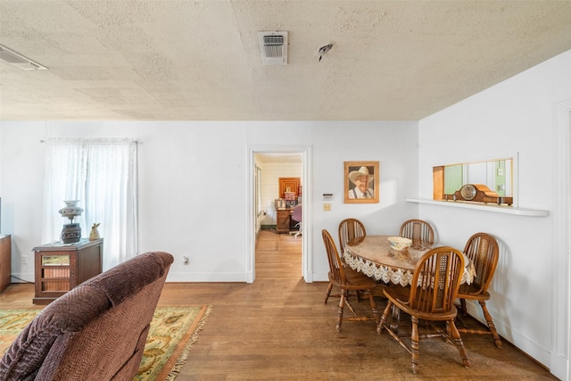 2506 Brazeal St, Waller, TX 77484 - dining area featuring a textured ceiling, baseboards, visible vents, and wood finished floors