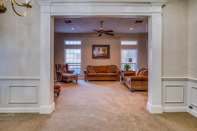 carpeted living room featuring crown molding, ceiling fan, a healthy amount of sunlight, and decorative columns