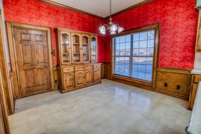 unfurnished dining area featuring crown molding and a chandelier