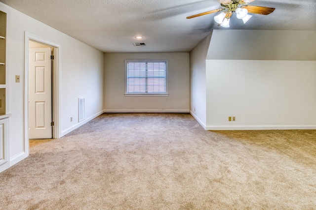 empty room featuring ceiling fan, light carpet, and a textured ceiling