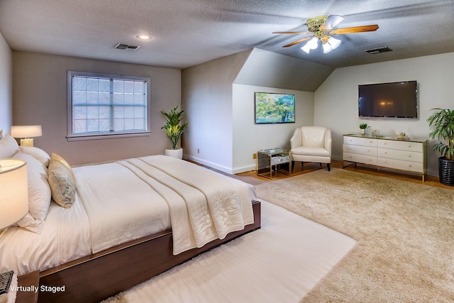 bedroom with ceiling fan, lofted ceiling, and a textured ceiling