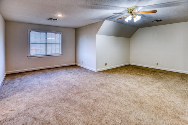 bonus room featuring vaulted ceiling, carpet, a textured ceiling, and ceiling fan