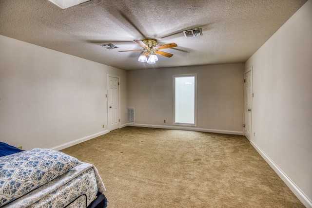 unfurnished bedroom with light carpet, a textured ceiling, and ceiling fan