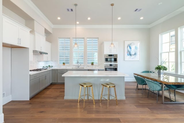 kitchen featuring gray cabinets, white cabinetry, a center island, ornamental molding, and decorative light fixtures