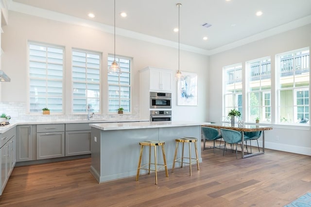 kitchen featuring sink, gray cabinets, backsplash, ornamental molding, and decorative light fixtures