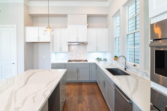 kitchen with sink, white cabinets, hanging light fixtures, light stone counters, and stainless steel appliances