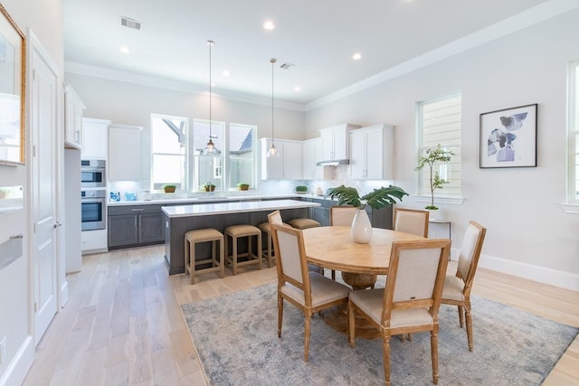 dining area with crown molding and light hardwood / wood-style floors