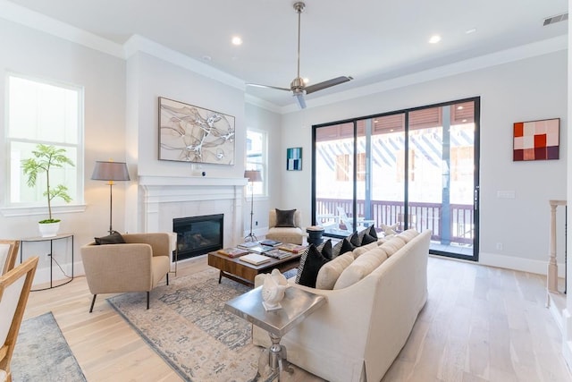 living room featuring ornamental molding, a tile fireplace, and light wood-type flooring