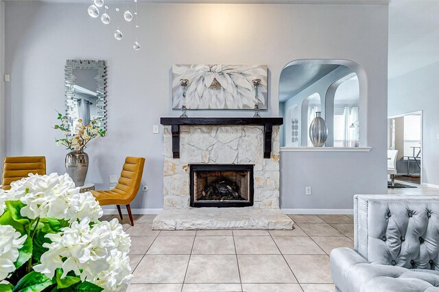 tiled living room featuring a stone fireplace