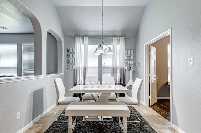 dining space with vaulted ceiling and light tile patterned floors